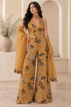 Full-length model view of the mustard floral embroidered halter top, wide-leg palazzo trousers and sheer scarf in an ivory room.