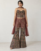 AI-styled model view: Woman standing front-facing in the embroidered three-piece outfit against an ivory wall.